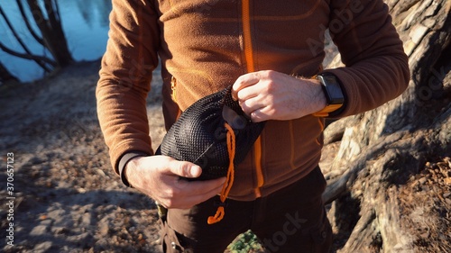 The theme of tourism is hiking and traveling in nature. Hands Caucasian man unpacking, setting the opening of the cover to get the pot kettle for cooking, boil water in the forest