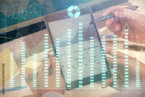 Double exposure of man's hands holding and using a phone and financial chart drawing. Market analysis concept.