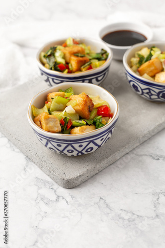 Tofu and Vegetables Stir Fry in Blue and White Bowls on White Background
