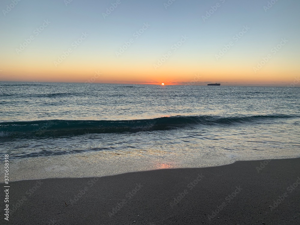 Landscape view of vibrant sunset over calm sandy beach shoreline