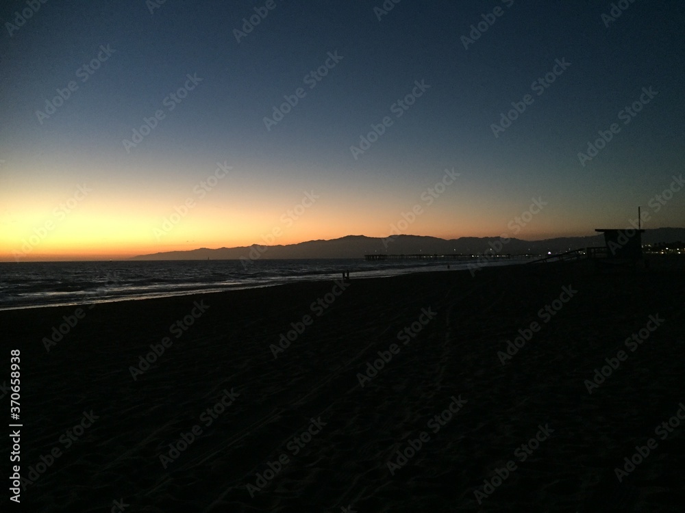 Landscape view of ocean coastline from dark sandy beach at sunset