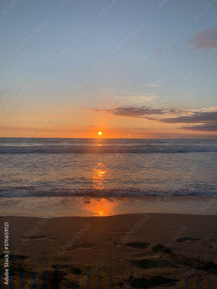 Fototapeta premium Seascape view of vibrant sunset over calm beach waters