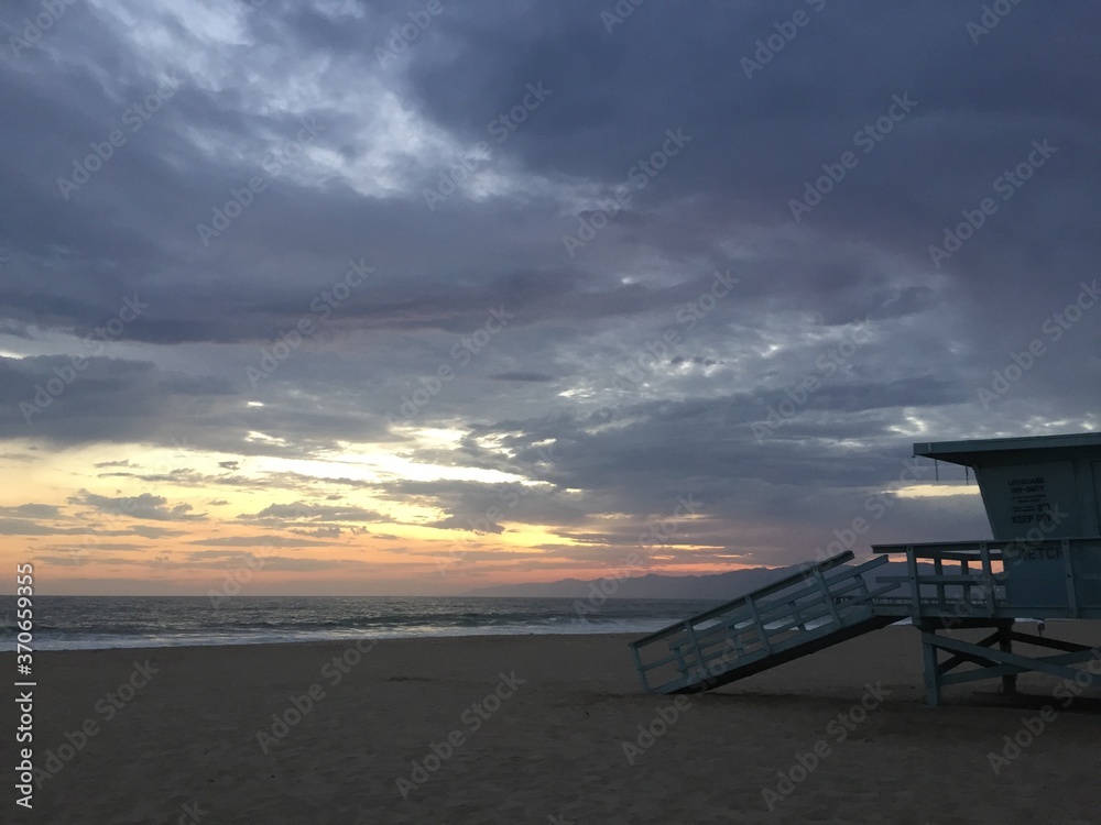 Landscape view of lifeguard tower on empty sand beach at sunset