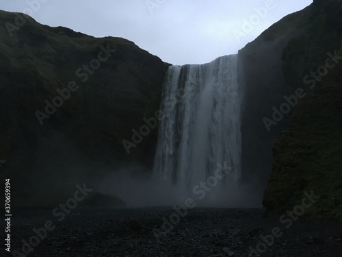 Landscape view of misty green mountain waterfall 