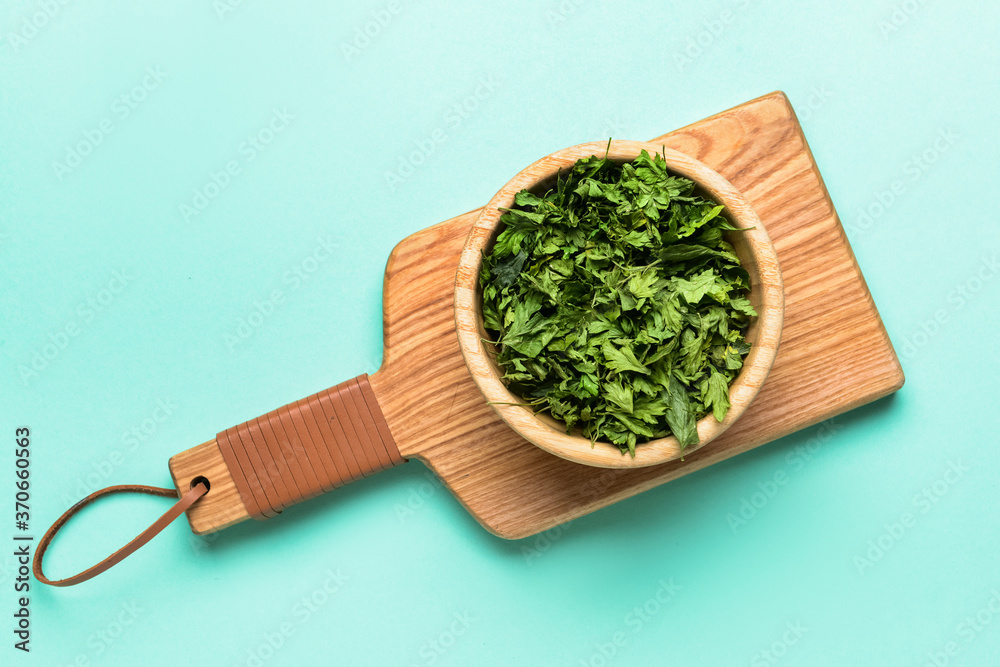 Bowl with dry parsley on color background