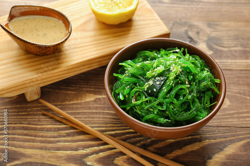 Bowl with tasty seaweed salad on table