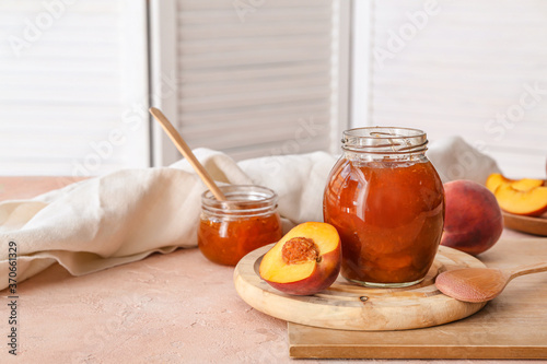 Jar with tasty peach jam on table