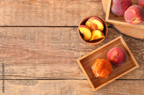 Jar with tasty peach jam on table