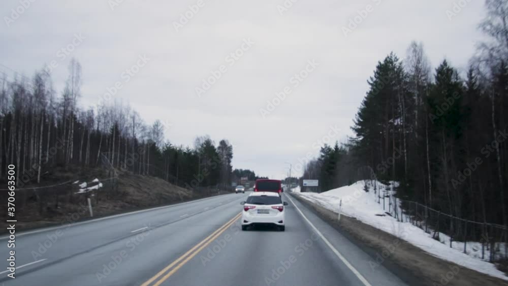 POV car: traveling and driving behind vehicles on three lane asphalt highway in rural countryside from Helsinki to Vuokatti Finland on cloudy sky cold winter day, handheld POV car: traveling and driving behind vehicles on three lane asphalt highway in rural countryside from Helsinki to Vuokatti Finland on cloudy sky cold winter day, handheld