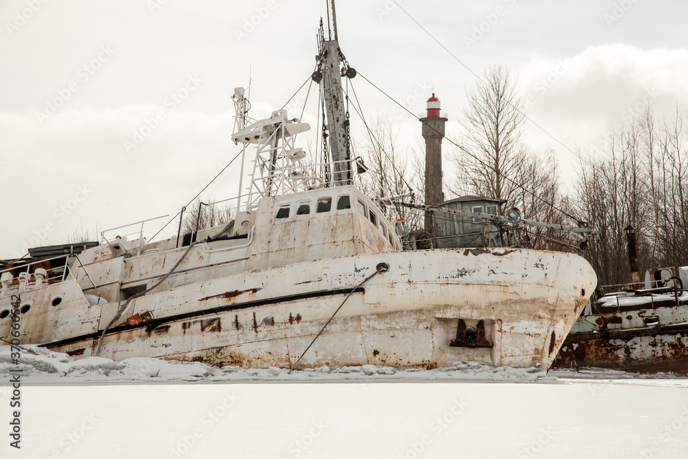 Fototapeta premium Abandoned white ship frozen in ice near lighthouse