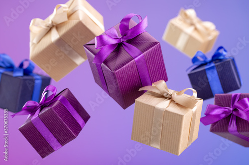 Gifts in flying boxes wrapped in blue, purple and craft paper with bow on bright background. Holidays and greeting card concept.