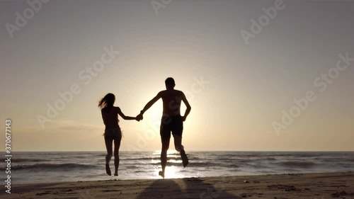 Wallpaper Mural silhouette couple on a beach holding hands and running to the sea. recorded at 60fps Torontodigital.ca