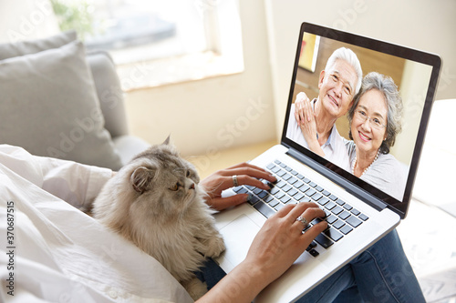young asian woman talking chatting with parents via video call using laptop computer