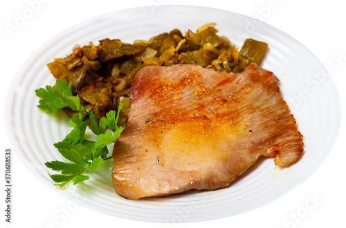 Close-up fried pork meat chops with stewed beans at plate. Isolated over white background