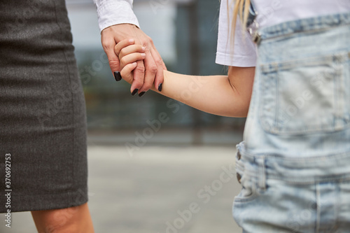 Business woman walking with her daughter while keeping her arm