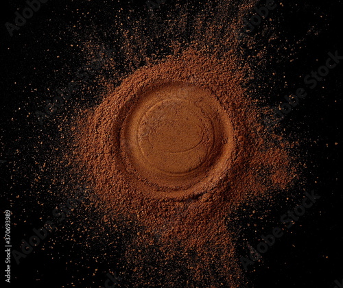 Cinnamon powder pile isolated on black background, top view