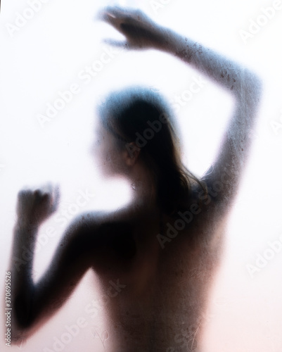 Silueta de una mujer hermosa posando de espaldas sobre un cristal