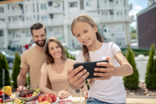 Pretty girl in white tshirt making selfie with parents