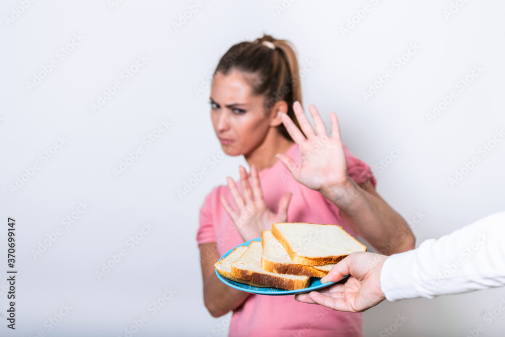 Young woman suffers from a gluten. Gluten intolerant and Gluten free diet concept, Real people. Copy space. Gluten intolerance and diet concept. Woman refuses to eat white bread. Focus on bread Young woman suffers from a gluten. Gluten intolerant and Gluten free diet concept, Real people. Copy space. Gluten intolerance and diet concept. Woman refuses to eat white bread. Focus on bread