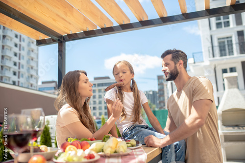 Young family having dinner outside and looking pleased