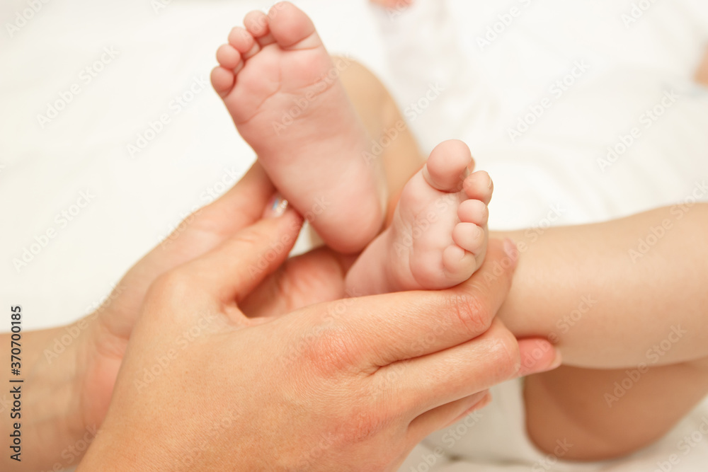 Hands of woman holds baby foot, blurred background Hands of woman holds baby foot, blurred background