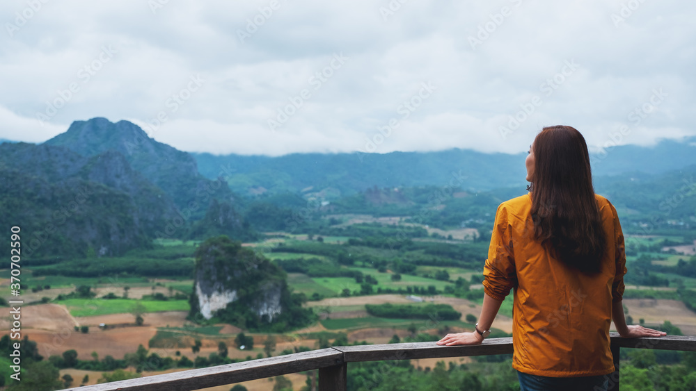 Rear view image of a female traveler looking at a beautiful foggy mountain and nature view