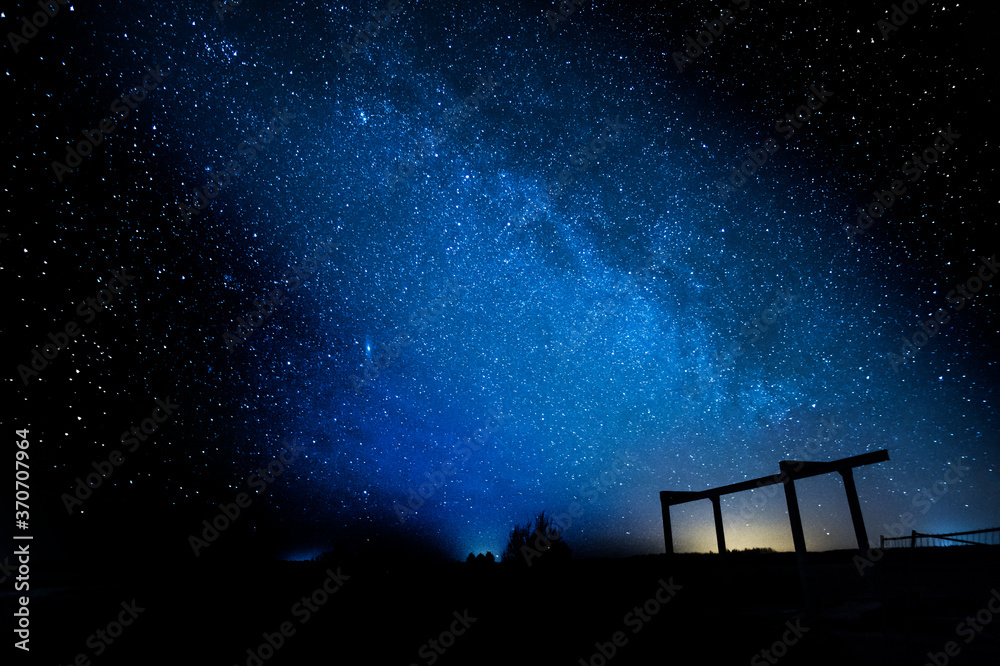 Fototapeta premium Milky way galaxy with trees and construction in the background.