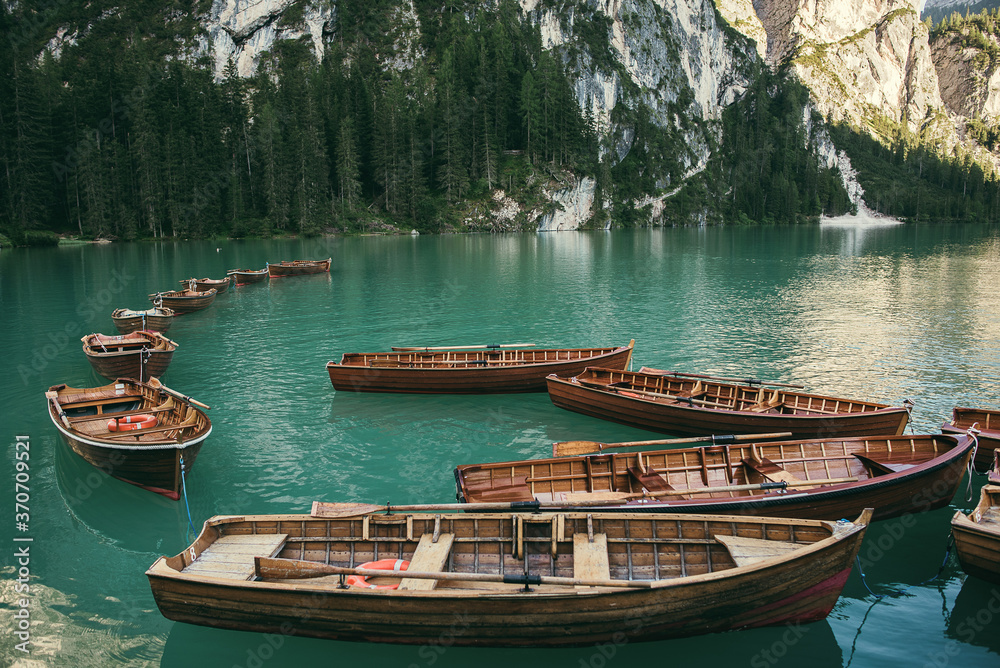 Wooden rowing boats parked in a dock. Mountain landscape with lake or river with forest and trees.