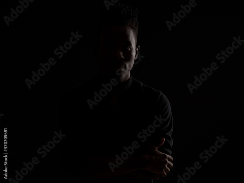 dramatic portrait of a young African man in a black shirt against a black background