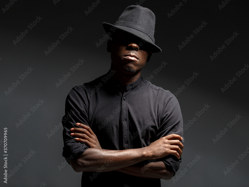 portrait of a young African man in a black hat. Black background studio photography portrait of a young African man in a black hat. Black background studio photography