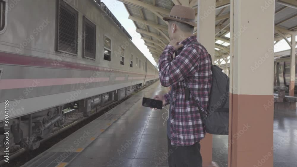 The young man who was waiting for the train was about to travel and was playing on the phone. The young man who was waiting for the train was about to travel and was playing on the phone.