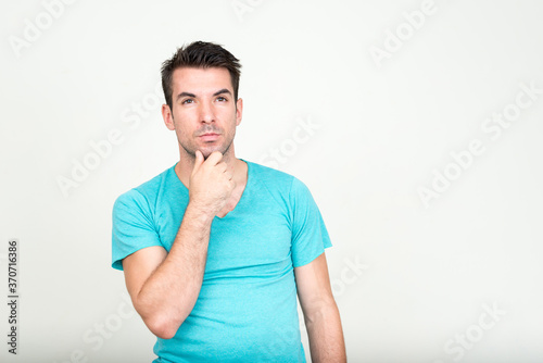 Portrait of young handsome Hispanic man against white background