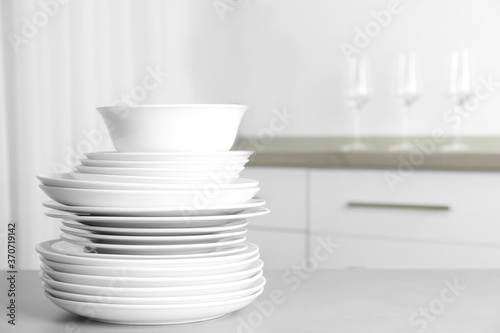 Stack of clean plates on grey table in kitchen. Space for text