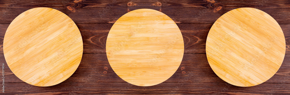 Top view of three empty wooden plates for pizza on dark brown wood background, kitchenware, flat lay Top view of three empty wooden plates for pizza on dark brown wood background, kitchenware, flat lay