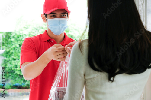 Asian food delivery man wearing face mask give food bag to female customer in front of the home.(selective focus)