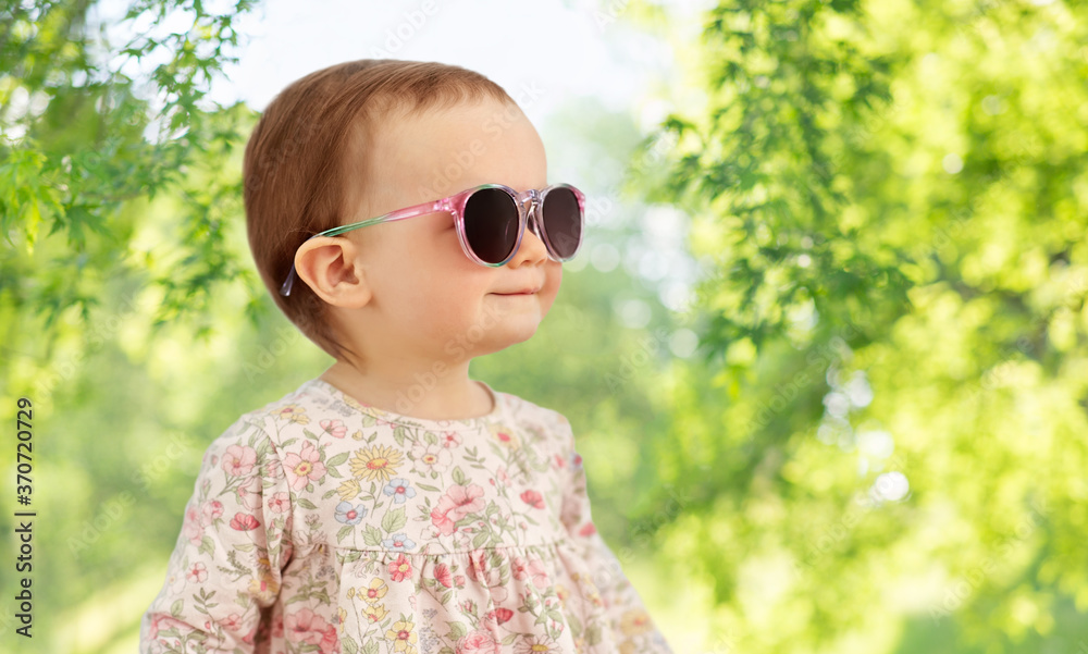 childhood, summer and people concept - happy little baby girl in sunglasses over green natural background childhood, summer and people concept - happy little baby girl in sunglasses over green natural background