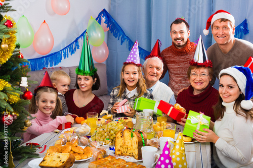 Cheerful smiling family exchanging gifts during Christmas dinner