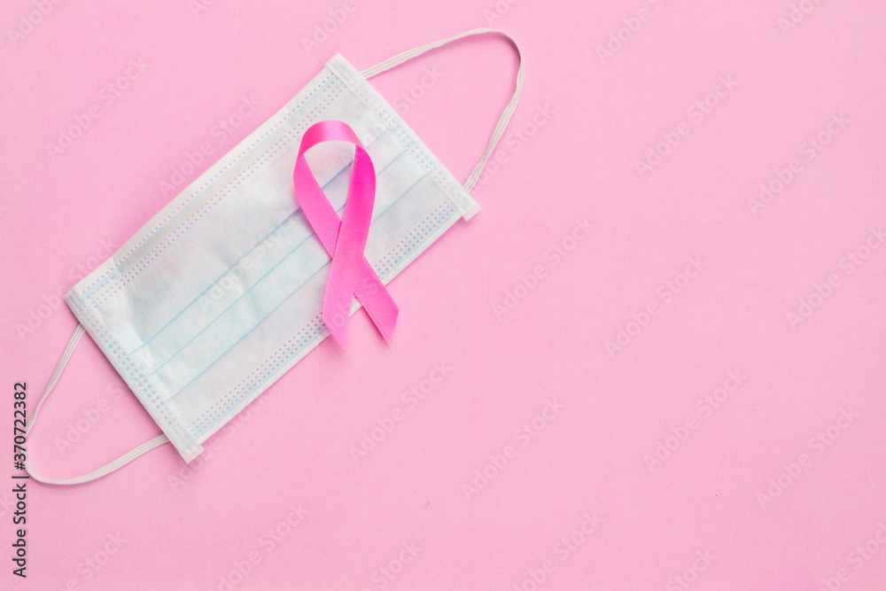 Breast Cancer concept : Top view pink ribbon and protective mask symbol of breast cancer campaign on pink