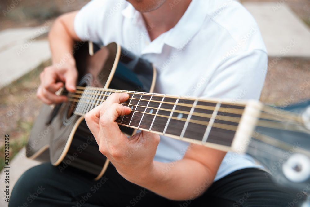 Close up photo of man playing at acoustic guitar.