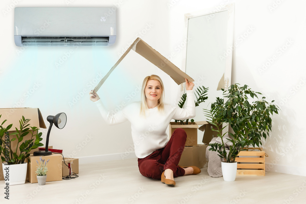 Happy woman breathing fresh air sitting. woman in a new apartment under air conditioning Happy woman breathing fresh air sitting. woman in a new apartment under air conditioning