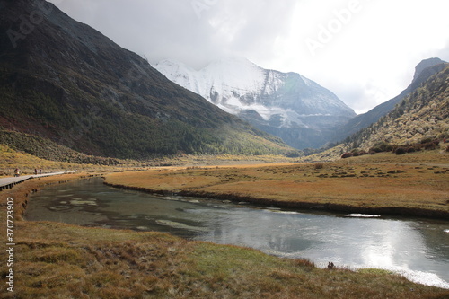 View of the sacred Mount Jampayang  Chinese  Yangmaiyong  with  Chonggu meadow and river of Yading Nature Reserve at Shangri-La region during Autumn in Daocheng county  southwest of Sichuan Province  
