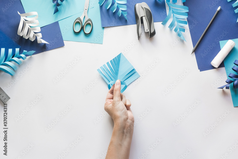 How to make paper beautiful Christmas toy snowflake to decorate room with children at home. Step by step instructions. Hands making DIY winter craft project. Step 7. Glue the opposite stripes How to make paper beautiful Christmas toy snowflake to decorate room with children at home. Step by step instructions. Hands making DIY winter craft project. Step 7. Glue the opposite stripes