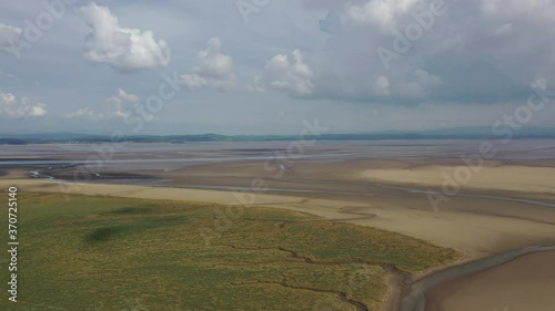 Aerial shot over a coastal bay when the tide is out, showing flat golden sand, bright sunny day. photo