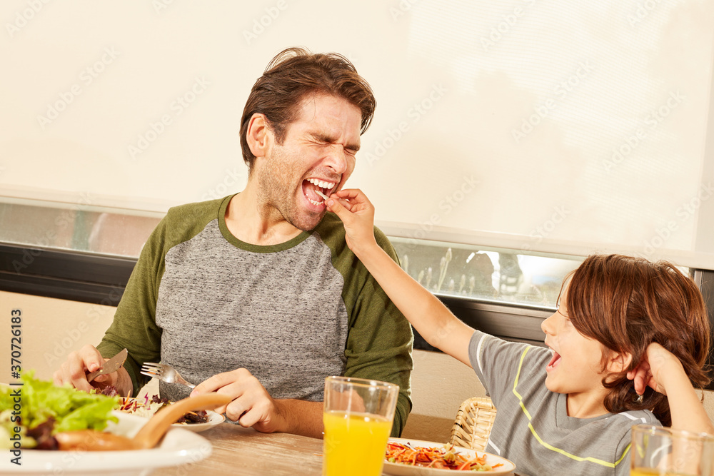 Junge füttert seinen Vater mit Salat und hat Spaß Stock Photo | Adobe Stock