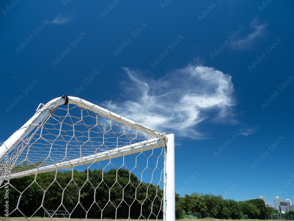 Fototapeta premium 真夏の青空と土のサッカーコートの風景