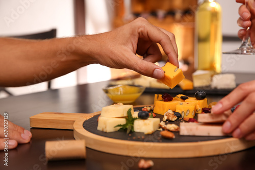 Couple with different types of delicious cheeses at table indoors, closeup