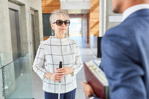 Blinde alte Frau mit Blindenstock im Business Büro photo