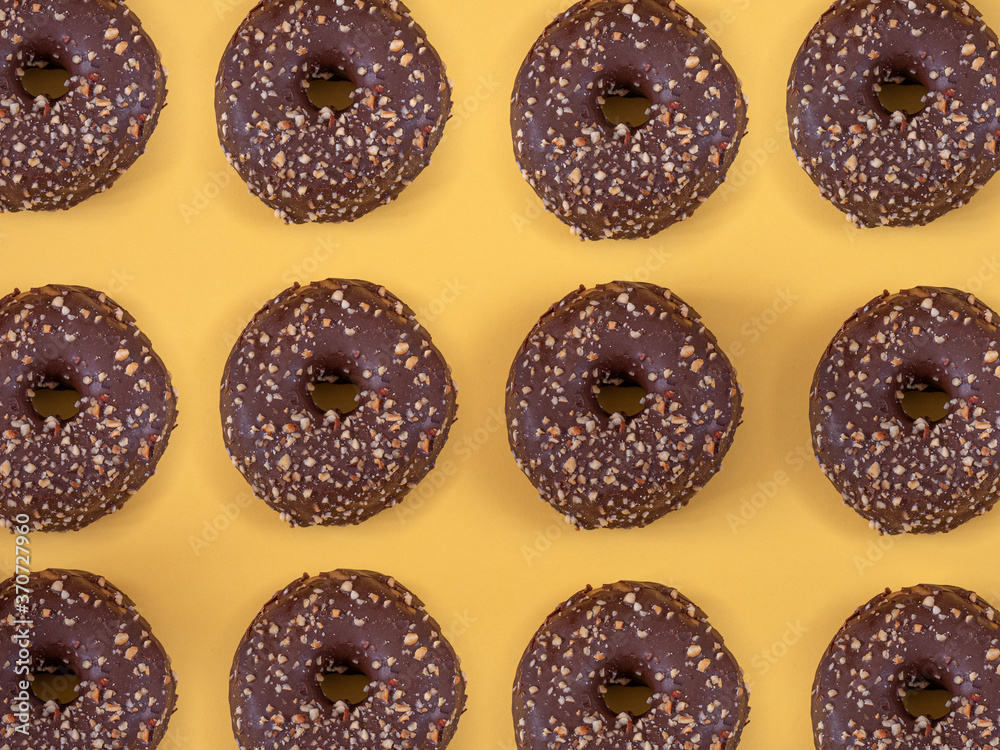 Chocolate donuts with almond pattern on yellow background