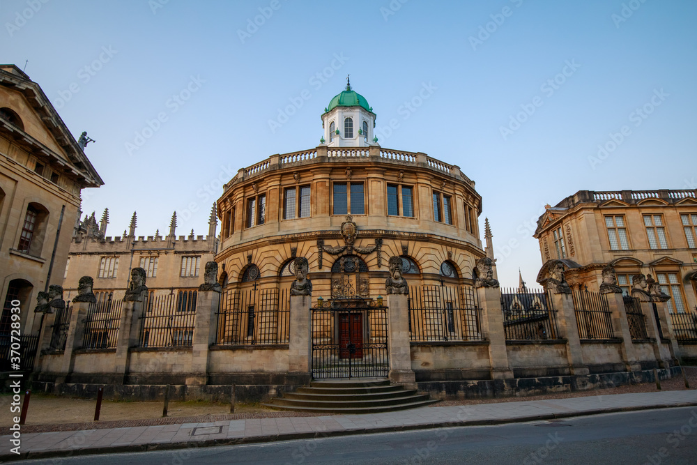 The Sheldonian Theatre and the statues around it, from Broad Street in Oxford with no people. Early in the morning. Oxford, England, UK.