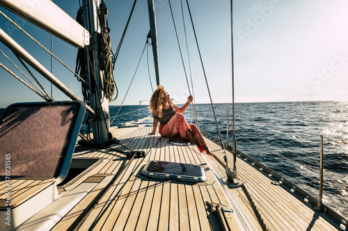 Beautiful young woman enjoy summer holiday vacation or excursion on sailboat with sun and ocean around - people enjoying life and lifestyle - travel and transport on sea concept